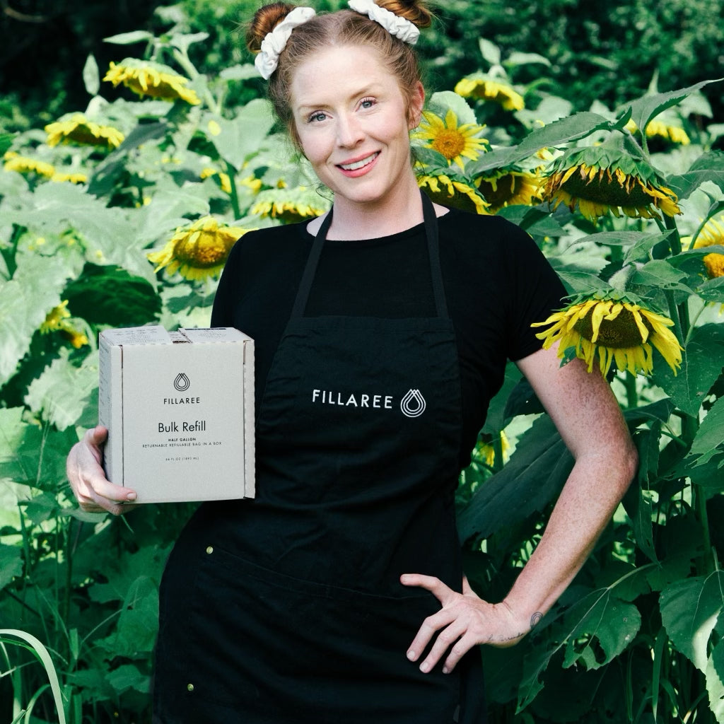 Alyssa is holding the new Bulk Refill Bag-in-a-Box in a field of sunflowers.