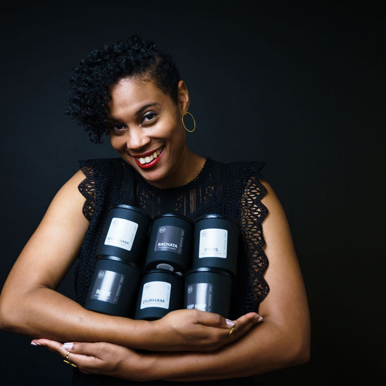 Tiffany Griffin, founder of Bright Black Candles, holding a variety of her handcrafted candles. Showcasing elegant black frosted glass vessels, each candle features rich, uplifting scents and a modern, minimalistic design, reflecting her passion for storytelling through fragrance.